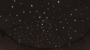 A room with a curved seating area, a patterned wall, and a ceiling with star-like lights. - Hotel Steinbock (Livigno)