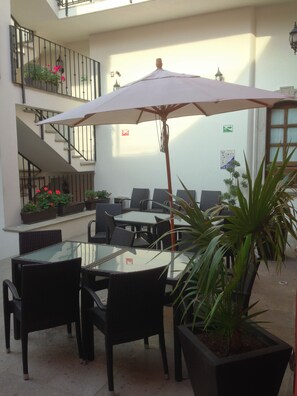 An outdoor seating area with tables and chairs, a staircase, and potted plants. - Hotel San Xavier (Querétaro)