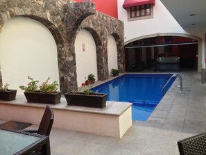 A pool area with stone arches and potted plants. - Hotel San Xavier (Querétaro)