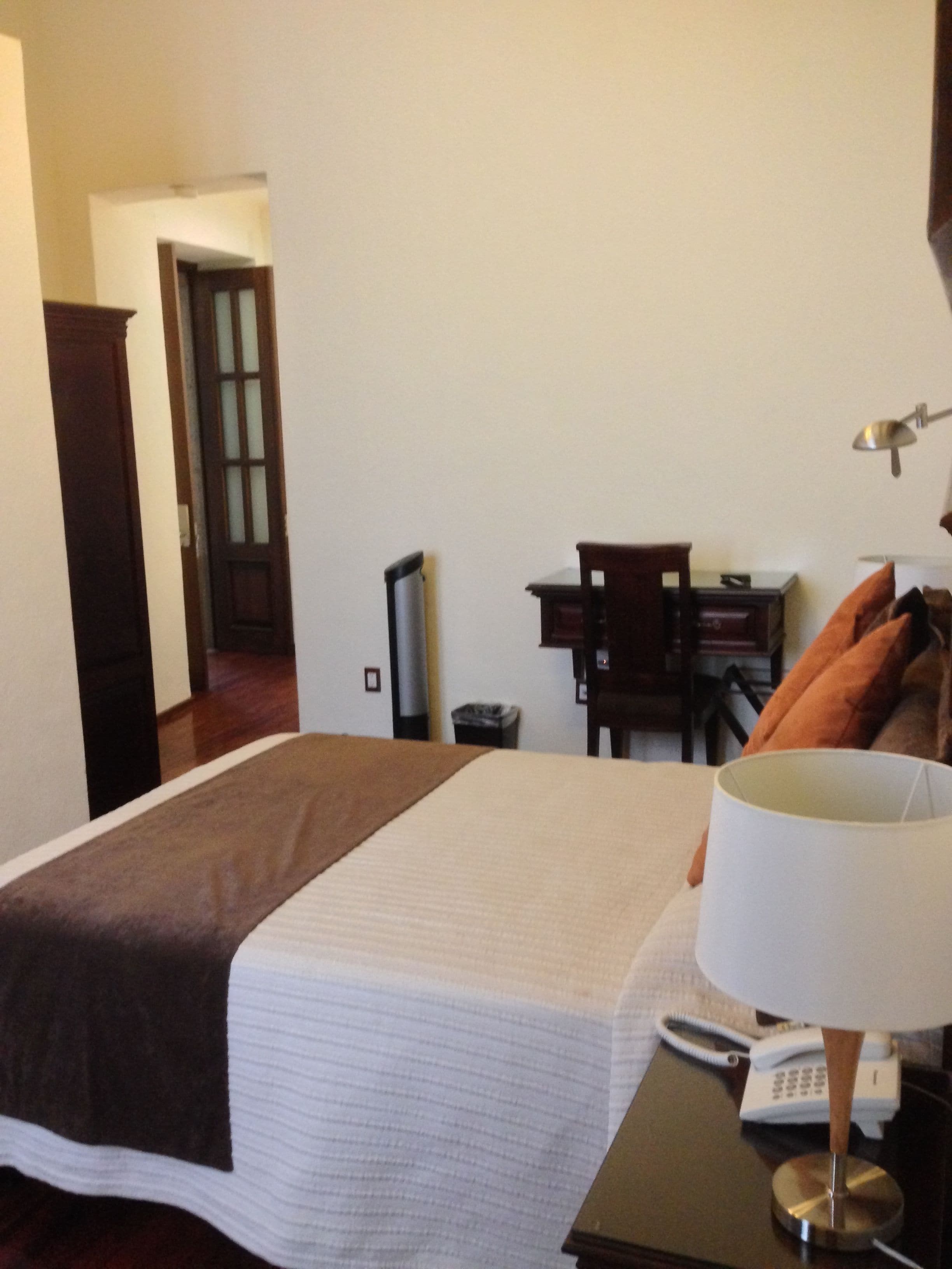 Una habitación de hotel con cama, escritorio, lámpara y teléfono.