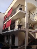 Un edificio de varios pisos con balcones, escaleras y plantas en macetas.
