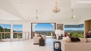 A spacious living room with a balcony, large windows, and a view of the landscape. - Alexandria Retreat (Doonan)