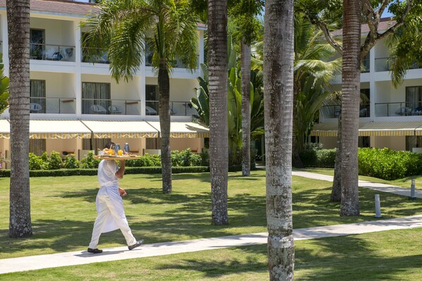 A hotel with a well-maintained lawn, palm trees, and a clear sky. - Viva V Samana by Wyndham, A Trademark Adults Resort (Las Terrenas)