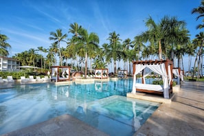 A pool area with palm trees, a gazebo, and lounge chairs.