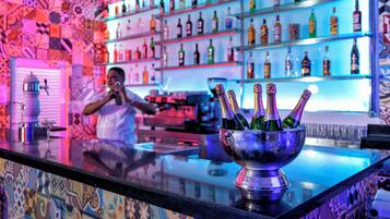 Una zona de bar con varios botellones en las estanterías y una jarra de champán en la barra.
