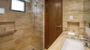 Un baño moderno con cabina de ducha de vidrio, puerta de madera, encimera de mármol y lavabo blanco.