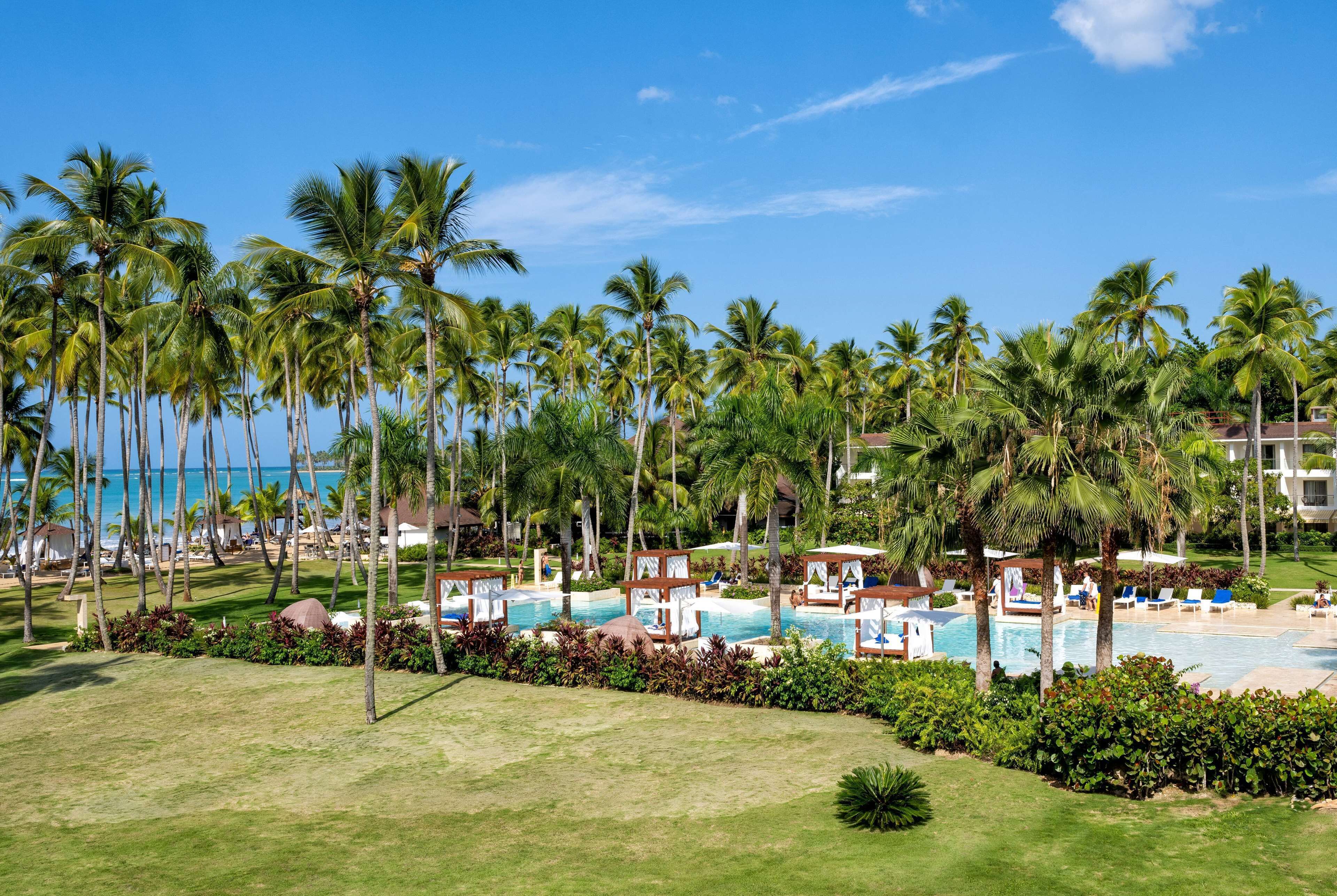 Um resort com área de piscina rodeada por palmeiras, praia e vista para o oceano.