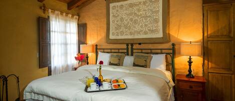 Une chambre élégamment aménagée, dotée d’un grand lit, d’un plateau de petit-déjeuner et d’une décoration murale.