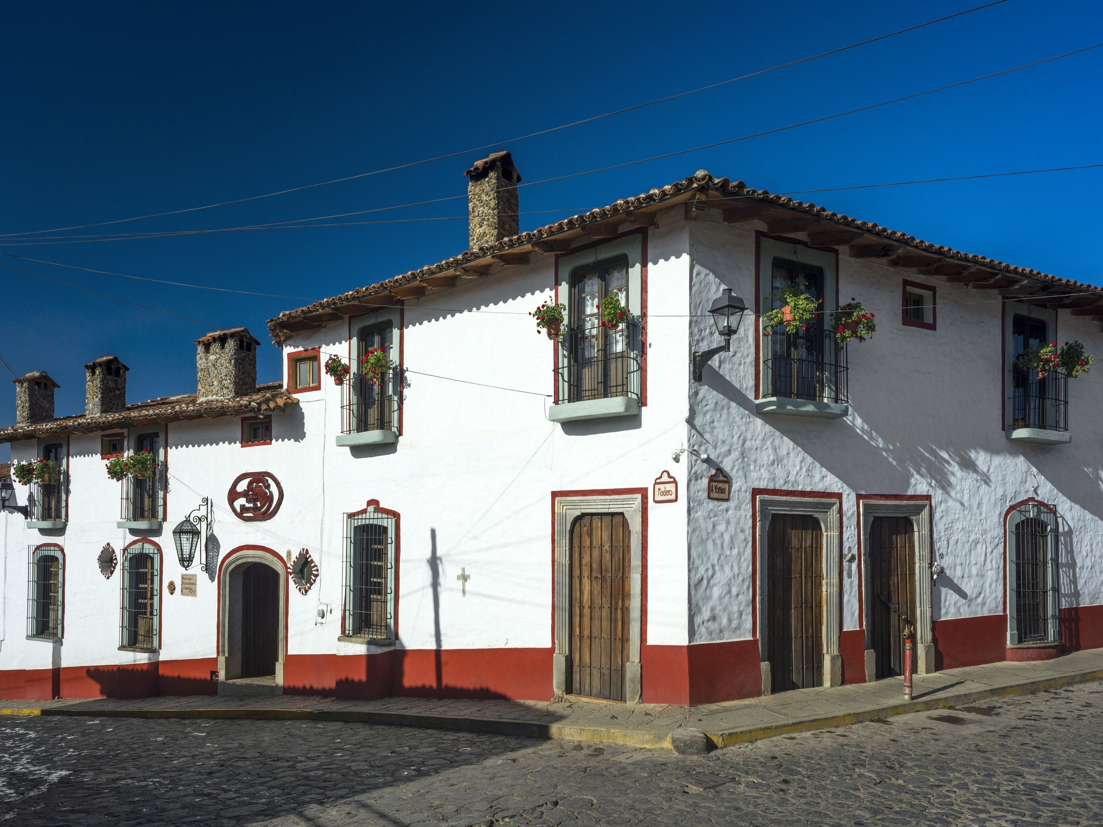 A traditional building with a white facade, red trim, and multiple windows with flower boxes.