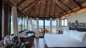 A hotel room with a large bed, a dining table with chairs, a coffee station, and a view of the beach. - La Valise Los Cabos, Member of Small Luxury Hotels (Vinorama)