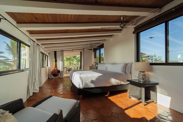 A bedroom with a bed, a nightstand, a lamp, and a view of the outdoors. - La Valise Los Cabos, Member of Small Luxury Hotels (Vinorama)
