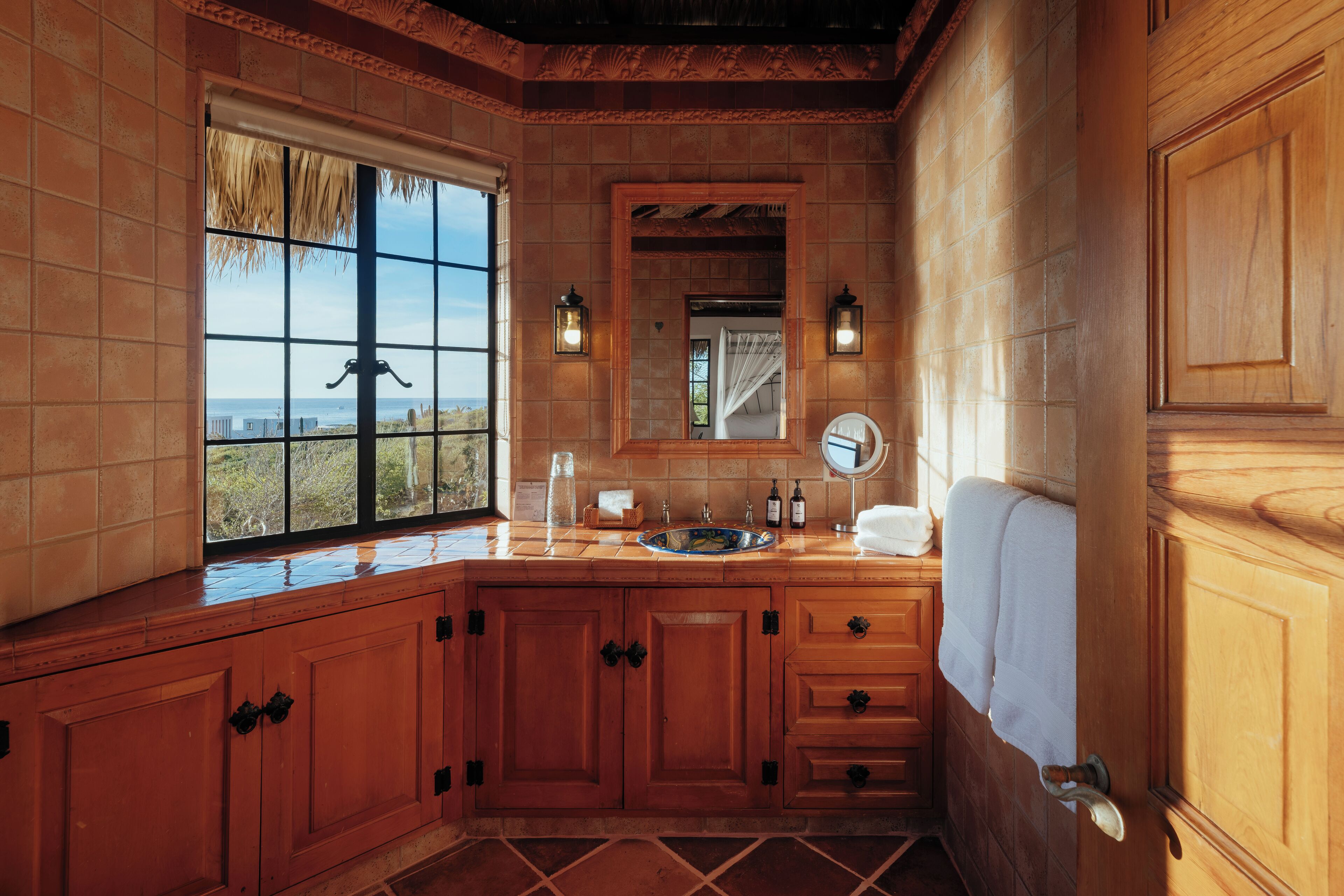 A wooden bathroom with a large window, a sink, and a mirror.