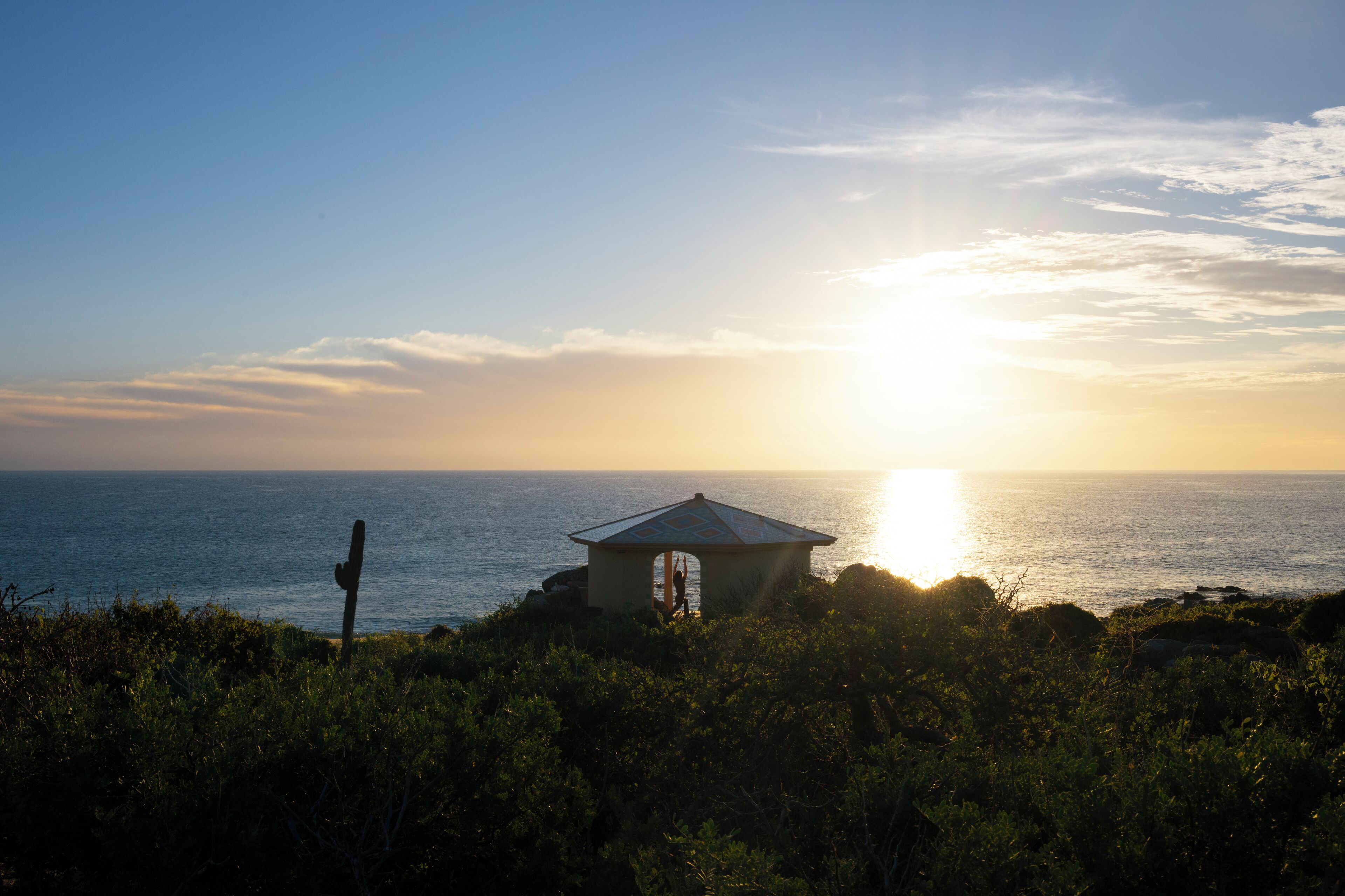 A gazebo overlooking the ocean at sunset.