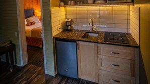 A compact kitchen with a microwave, sink, and wooden cabinets.
