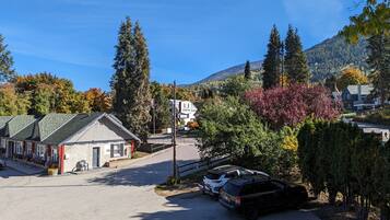 Uma pequena cidade com uma fileira de edifícios térreos, incluindo um hotel com uma placa. Há carros estacionados e um céu claro.
