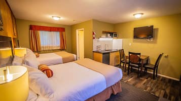 A hotel room with two beds, a desk with a microwave, a sink, and a TV.