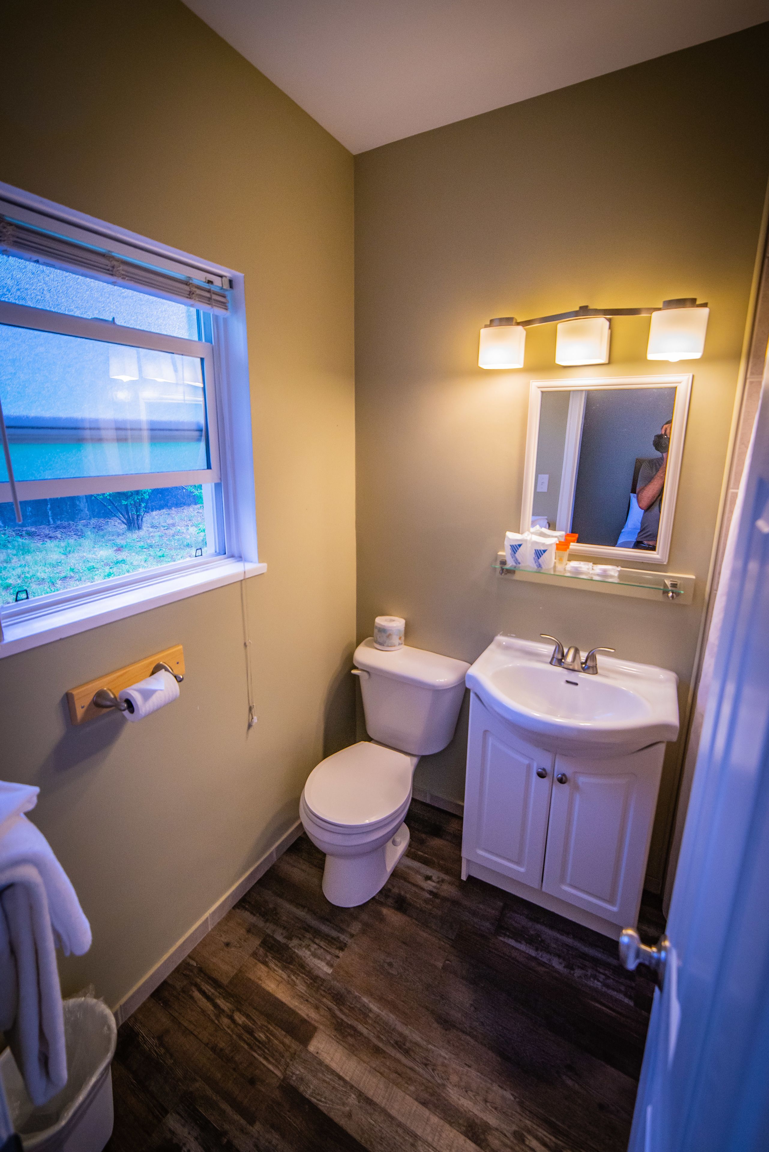 A bathroom with a toilet, sink, and window.