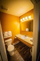 Un baño con inodoro blanco, lavamanos y espejo con iluminación.