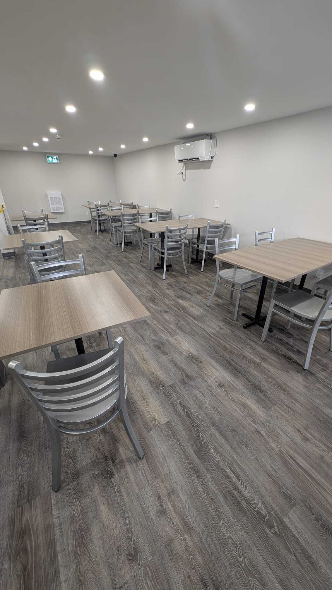 A conference room with grey wooden flooring, metal chairs, and tables.