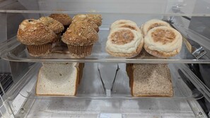 Bakery display case showcases a variety of freshly baked goods, including muffins and bread.