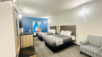 Una habitación de hotel con una cama, dos mesitas de noche, un sofá, un televisor y un ventilador de techo.