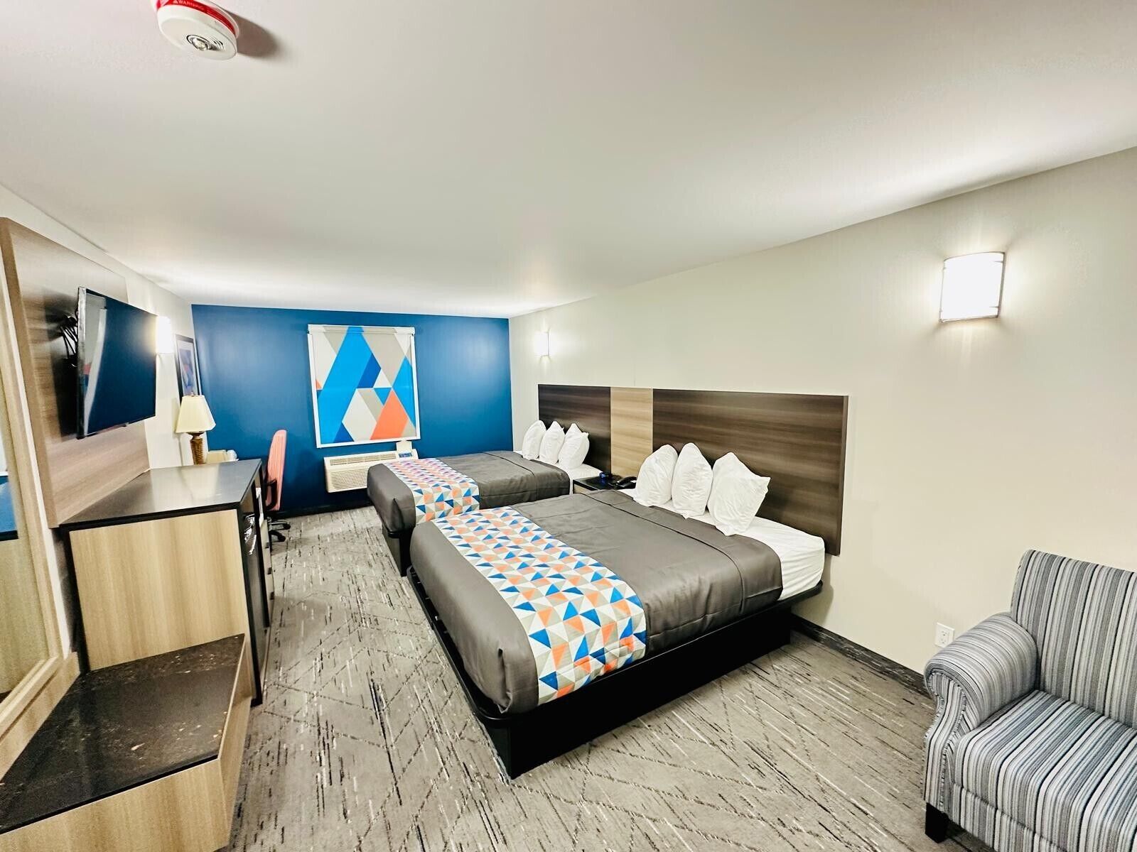 Una habitación de hotel con cama, escritorio, silla y televisor.