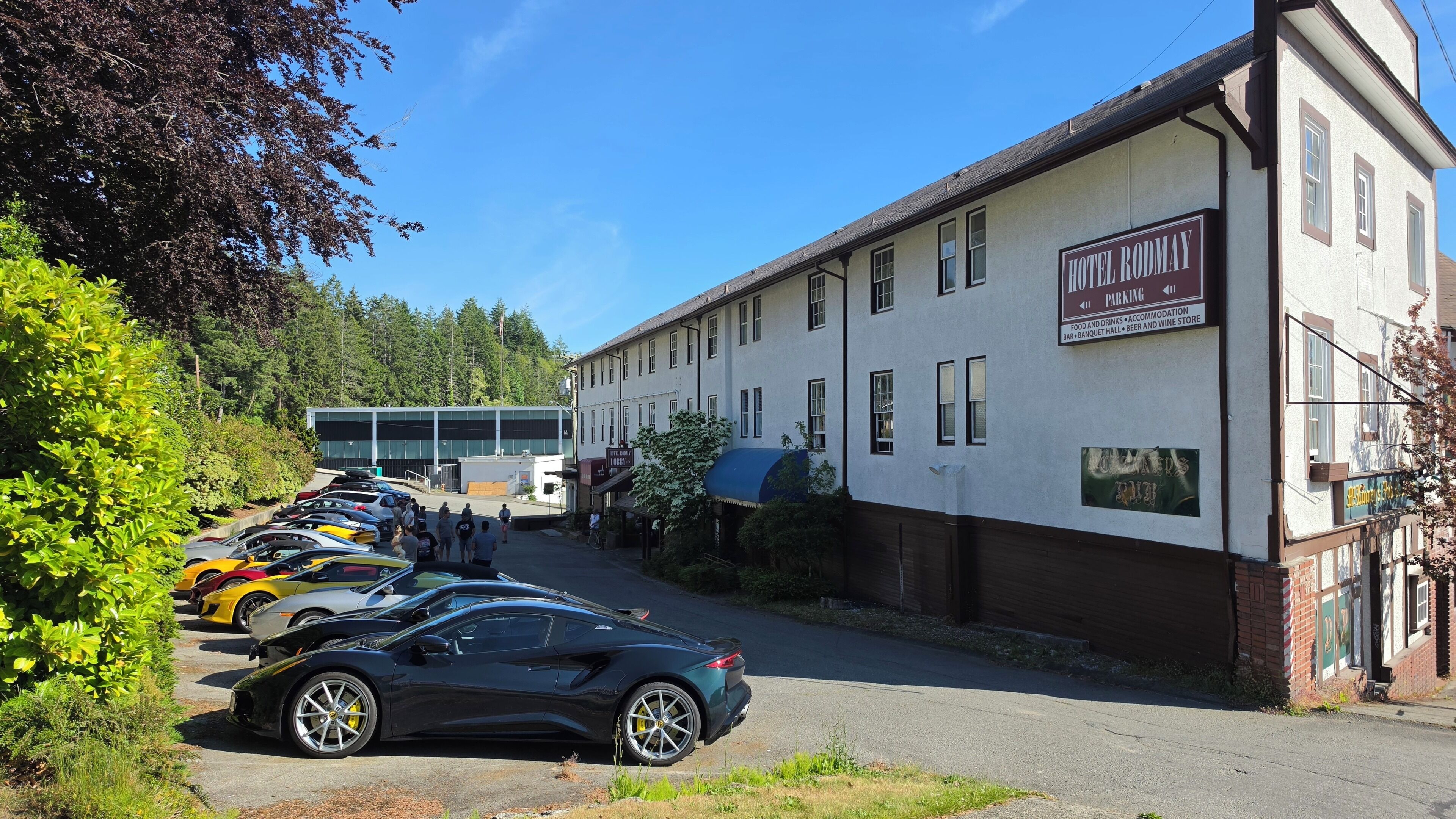 A hotel with a sign indicating parking, food and drinks, accommodation, bar, banquet hall, and a wine store.