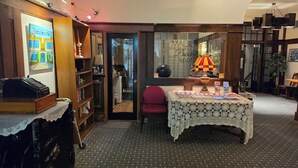 A room with a desk, chair, shelves with books, a lamp, and a map display. - Rodmay Heritage Hotel (Powell River)