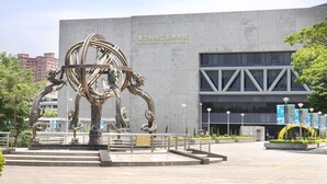 Een modern gebouw met een grote sculptuur ervoor.