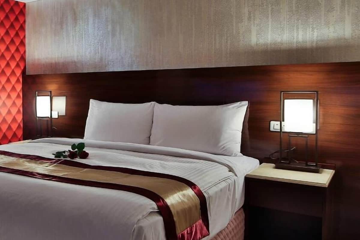 Une chambre d’hôtel avec un grand lit, deux tables de chevet et une tête de lit au motif texturé.