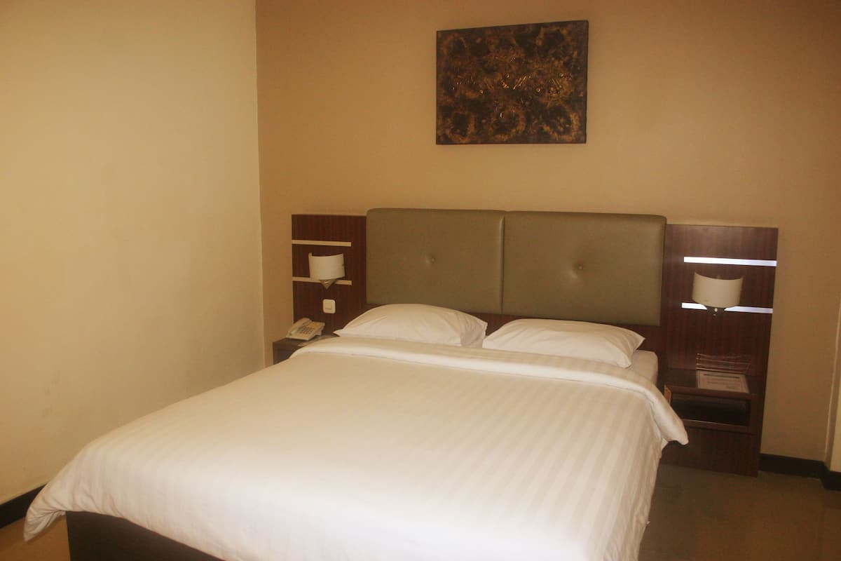 Una habitación de hotel con una cama, una mesita de noche, una lámpara y un cuadro en la pared.