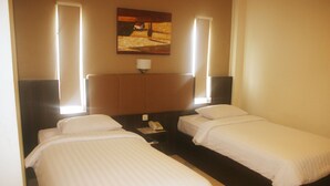 Une chambre d’hôtel avec deux lits simples, une table de chevet avec un téléphone et un tableau au mur.