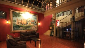 A spacious lobby with a large mural, leather seating, and a staircase. - Hotel Casa Madero (San Cristóbal de las Casas)