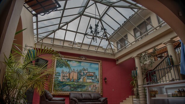 A spacious atrium with a high ceiling, a large mural, and a staircase leading to an upper level. - Hotel Casa Madero (San Cristóbal de las Casas)