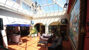 A spacious atrium with a high ceiling, a glass roof, and a central seating area with sofas and a coffee table. - Hotel Casa Madero (San Cristóbal de las Casas)