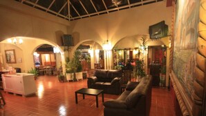 A spacious lobby with a high ceiling, leather sofas, a coffee table, and potted plants. - Hotel Casa Madero (San Cristóbal de las Casas)