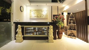 Un área de recepción de diseño moderno, con un reloj, un relieve decorativo, una vitrina de cristal y una estantería de madera con adornos.