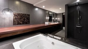 Un baño moderno con una bañera grande, un tocador de madera, un respingo de mármol y una zona de ducha oscura.