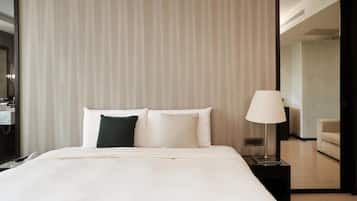 A hotel room with a bed, a nightstand, a lamp, and a view of the adjacent room.
