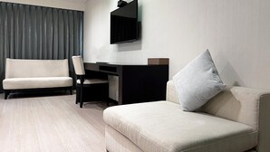 Una habitación de hotel moderna con sofá, escritorio y una silla.