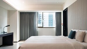 Una habitación de hotel moderna con una cama grande, un escritorio y una ventana con cortinas.