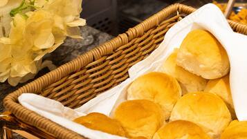 A wicker basket filled with rolls of bread, placed on a marble countertop.