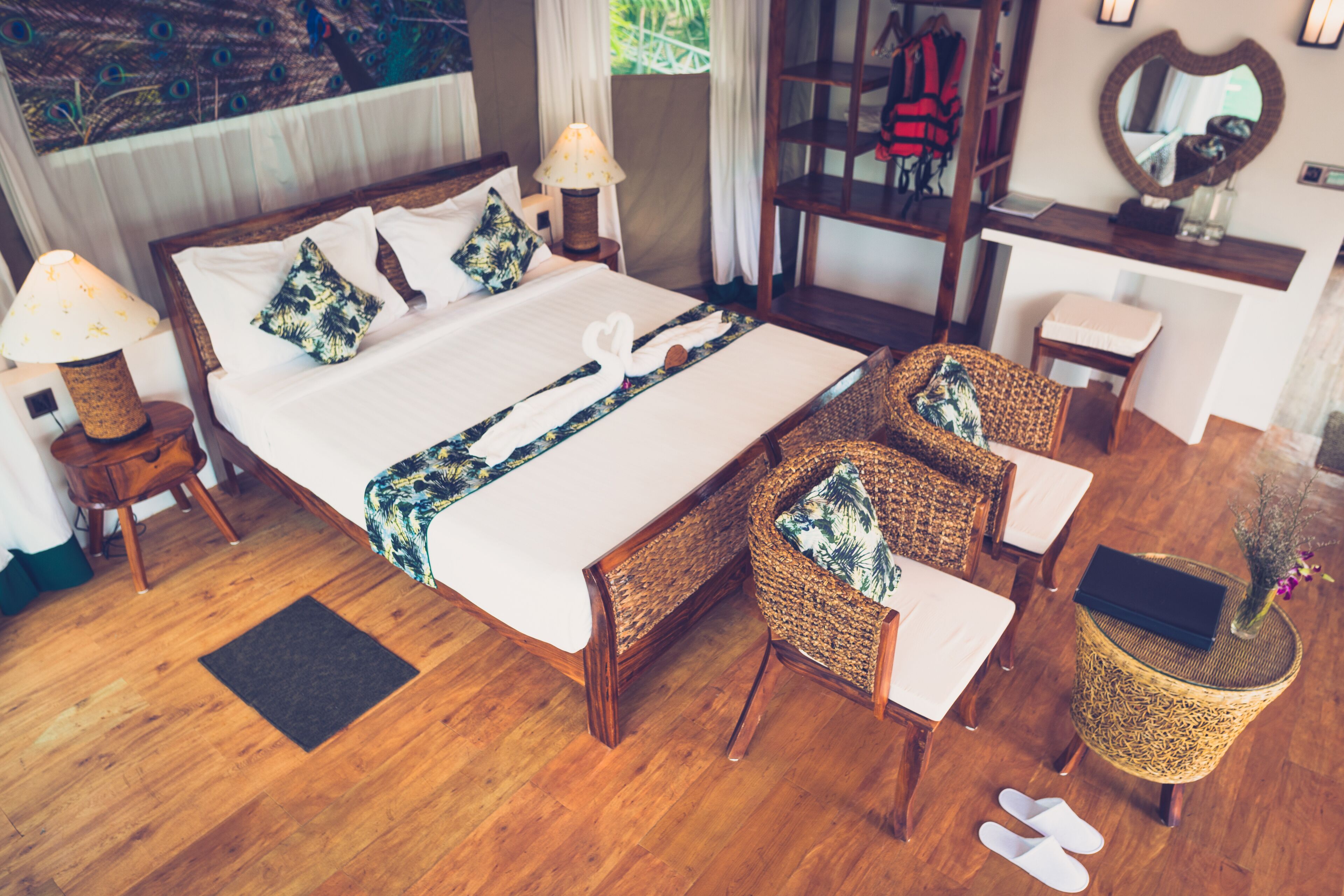 A hotel room with a large bed, two chairs, a desk, and a mirror.