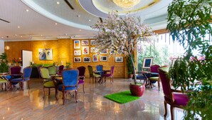 A hotel lobby with a large chandelier, a central tree, and a variety of colorful chairs and tables. - Yilan Fu Hsiang Hotel (Yilan)