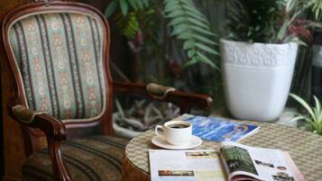 Una cadira amb un coixí estampat, una tassa de cafè i una revista sobre una taula.