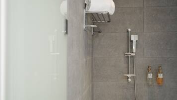 A modern bathroom with a glass shower enclosure, a towel rack, and two bottles of soap.
