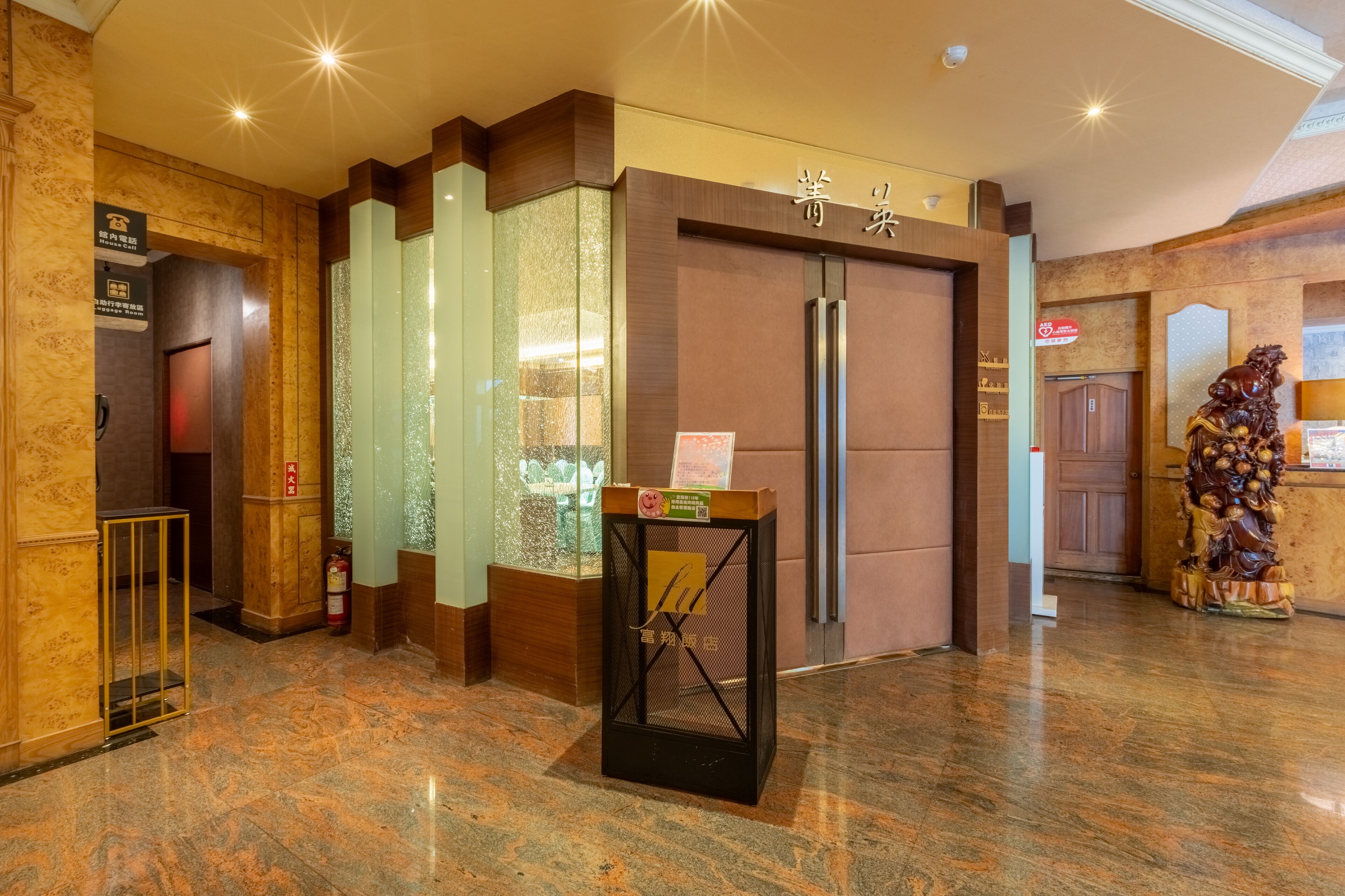 A hotel lobby with a reception desk, a glass display case, and a statue.