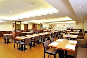 Una amplia sala de conferencias con varias mesas y sillas, equipada con documentos y una máquina de café.