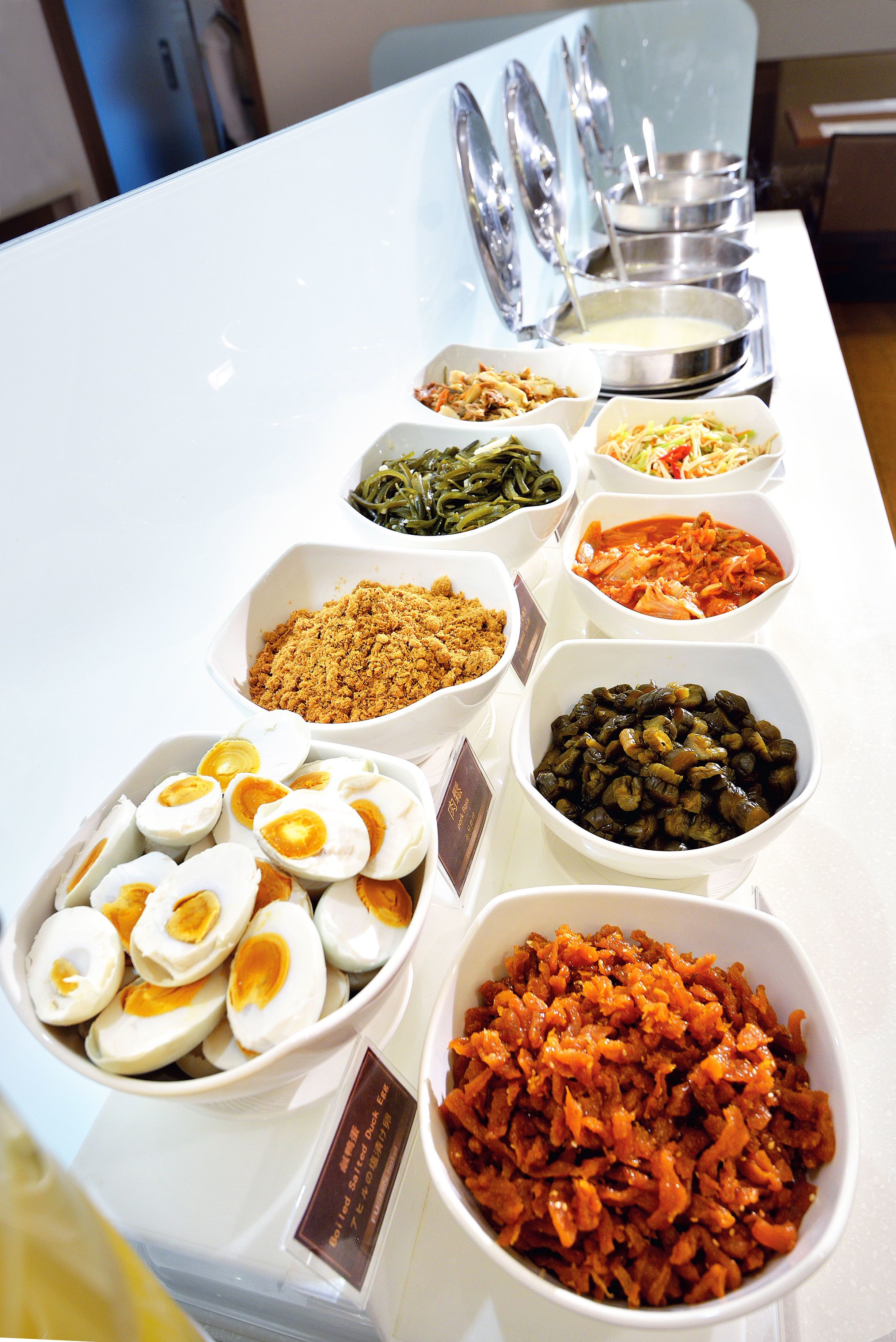 A buffet table with various food items including eggs, vegetables, and sauces.