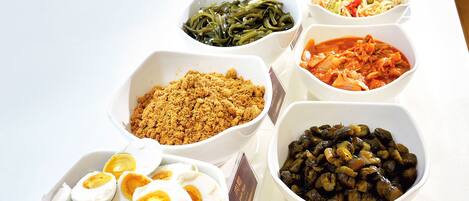 Uma mesa de buffet com diversos alimentos, incluindo ovos, vegetais e molhos.